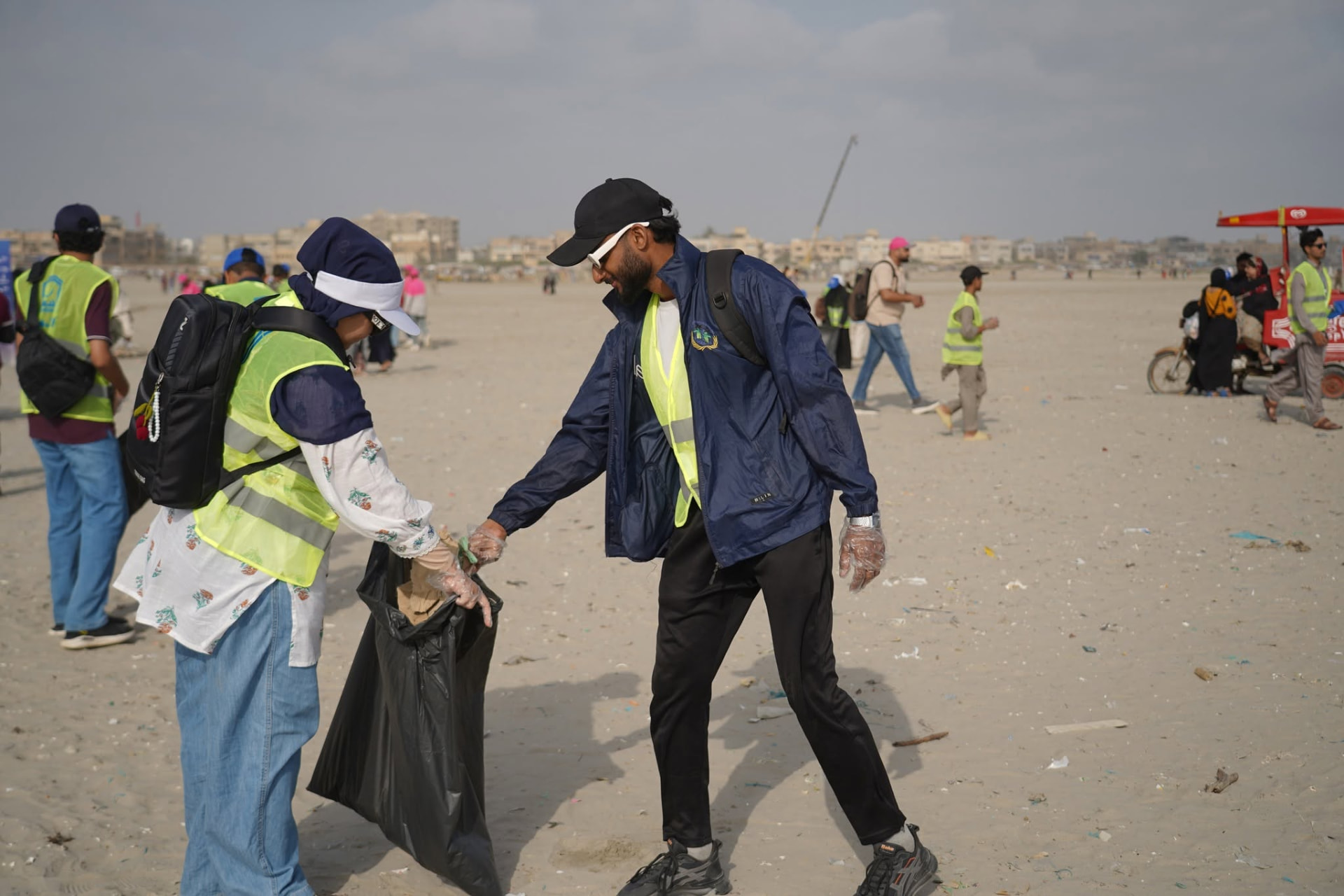 Community volunteers working together to collect litter from a Karachi beach